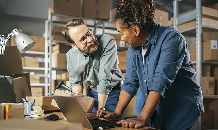 Happy Male and Female Working in Warehouse. Talking, Using Lapto